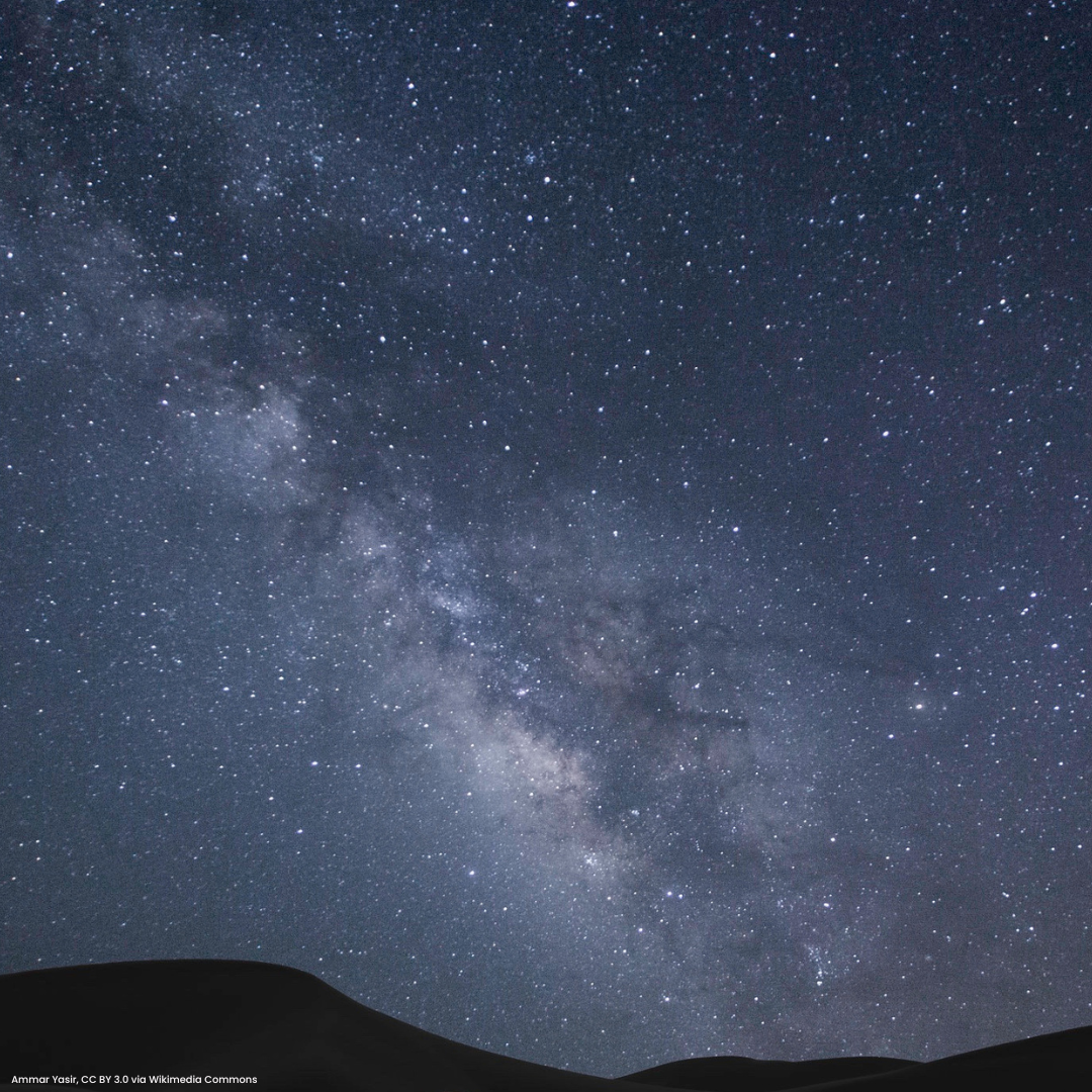Bluish night sky with the Milky Way angled above silhouetted hills.